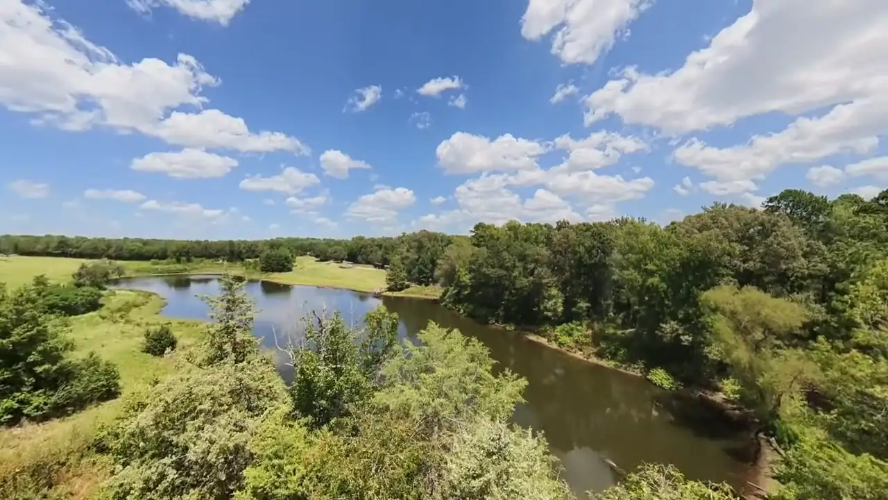 The upper pond seen from a wooded rise under a sky full of cumulus clouds